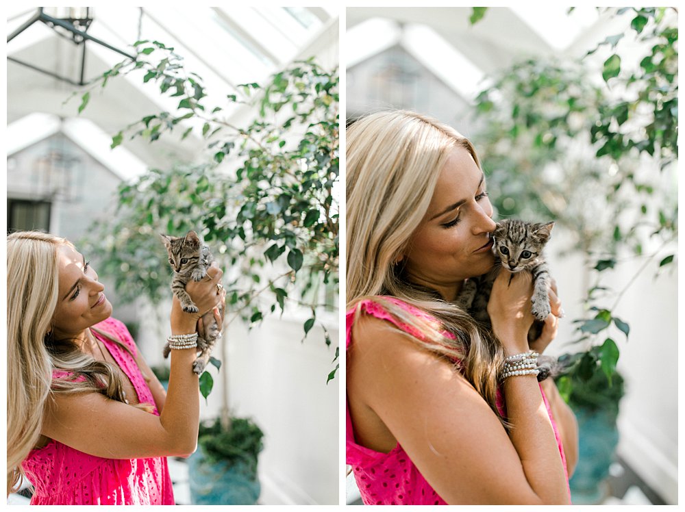 Blonde woman holding kitten in greenhouse