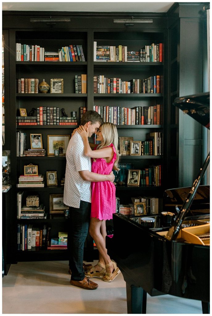Couple embracing in front of book shelf and grand piano in Dallas estate engagement