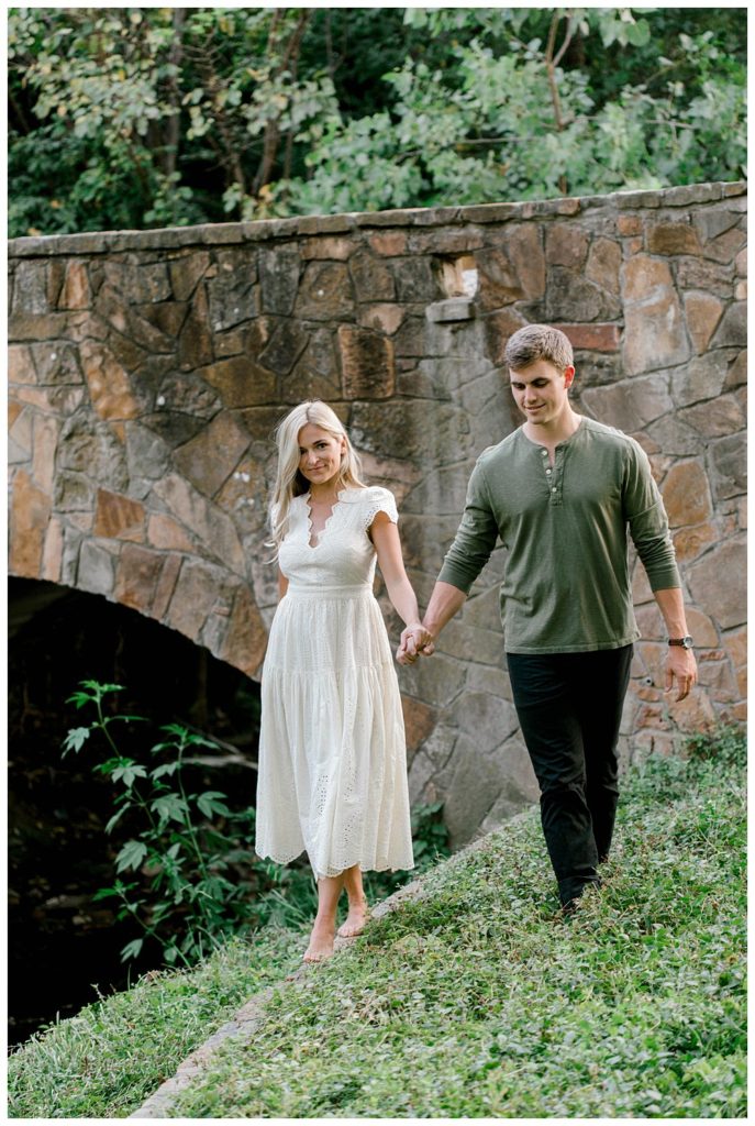 Couple walking hand in hand next to stone bridge