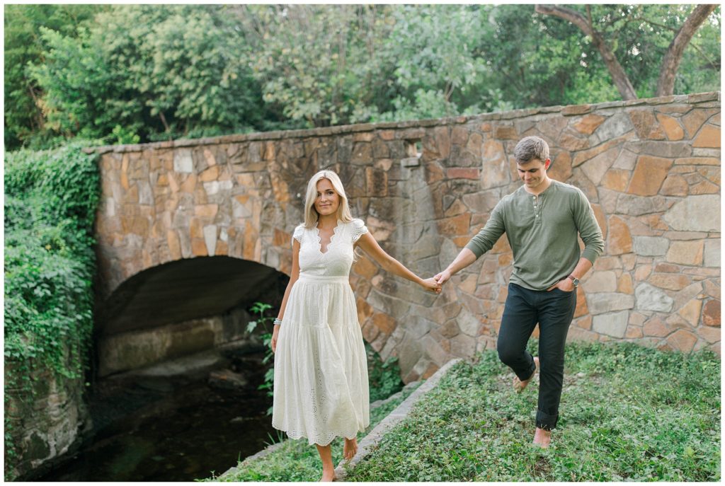 Couple walking hand in hand next to stone bridge