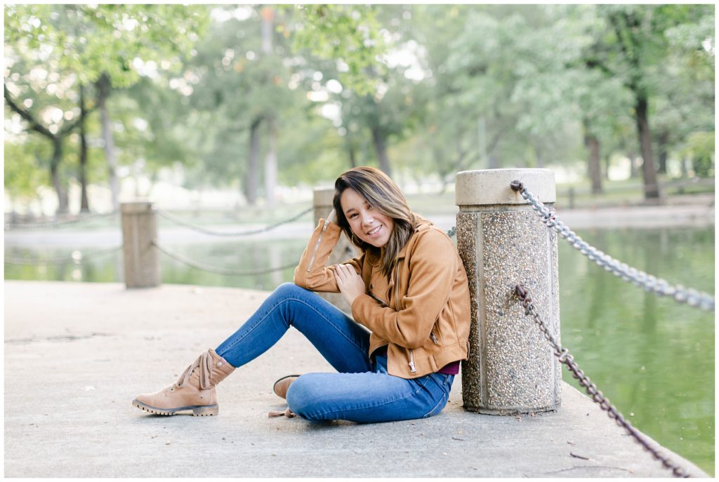 Girl sitting on cement next to pond in Fort Worth Trinity Park senior session