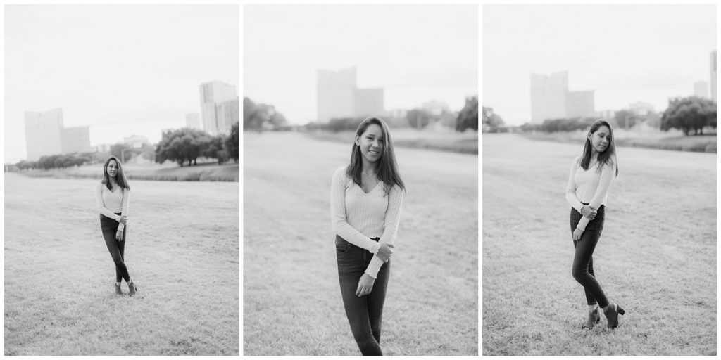 BW girl standing in field with cityscape behind her in Fort Worth Trinity Park senior session