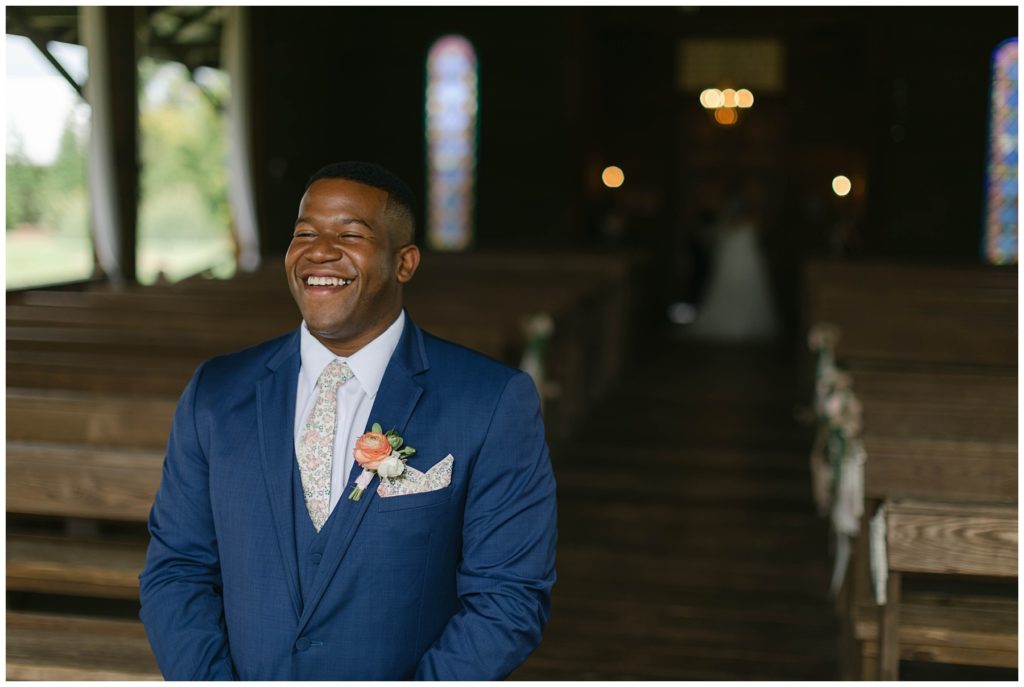Groom smiling before bride comes up to him for first look