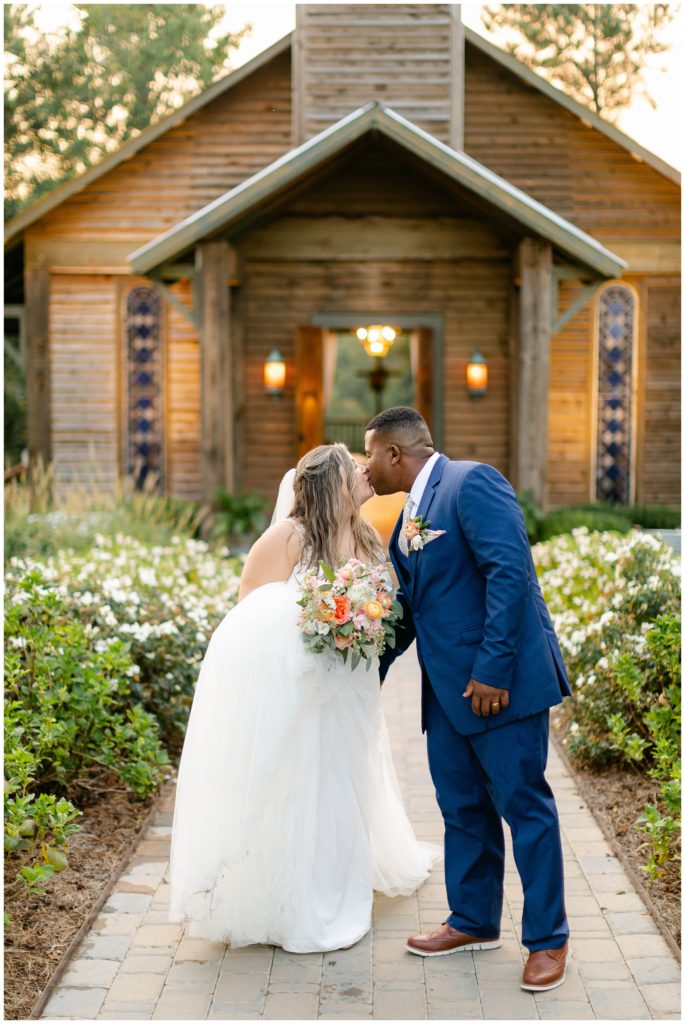 Bride and groom kissing in front of chapel at Pine Knoll Farms