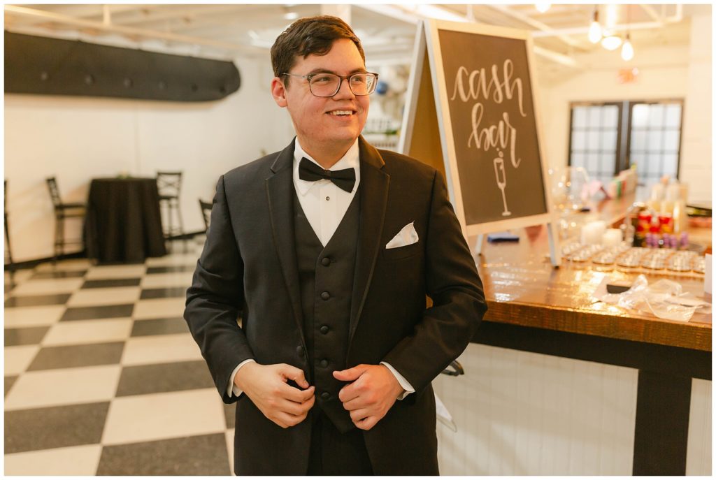 Groom standing in tux in Hugos on the square wedding