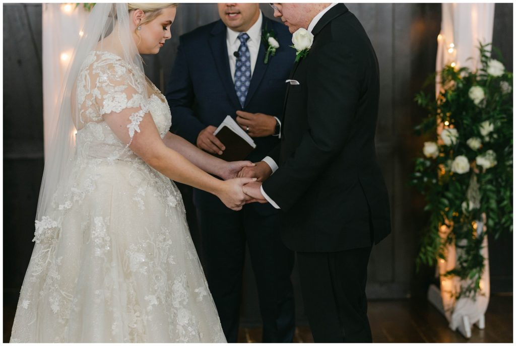 Bride and groom holding hands at alter