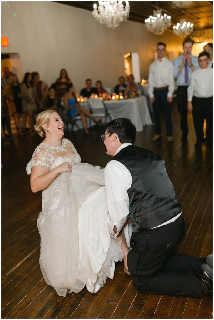 Groom removing garter from bride's leg at Hugos on the Square