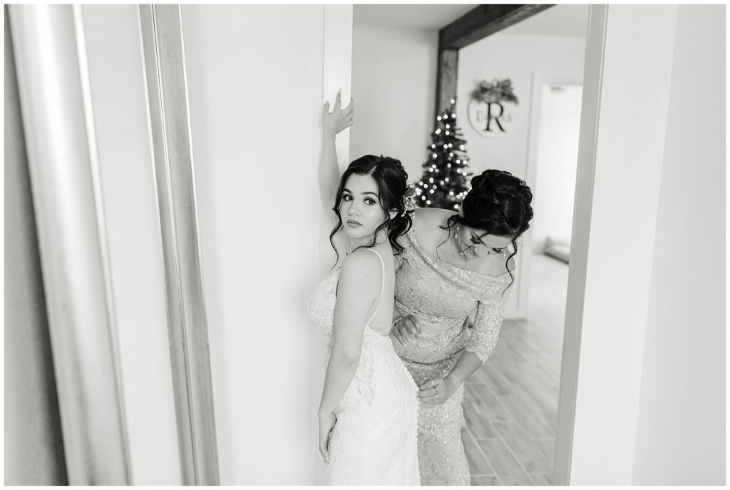 BW bride being buttoned into wedding gown