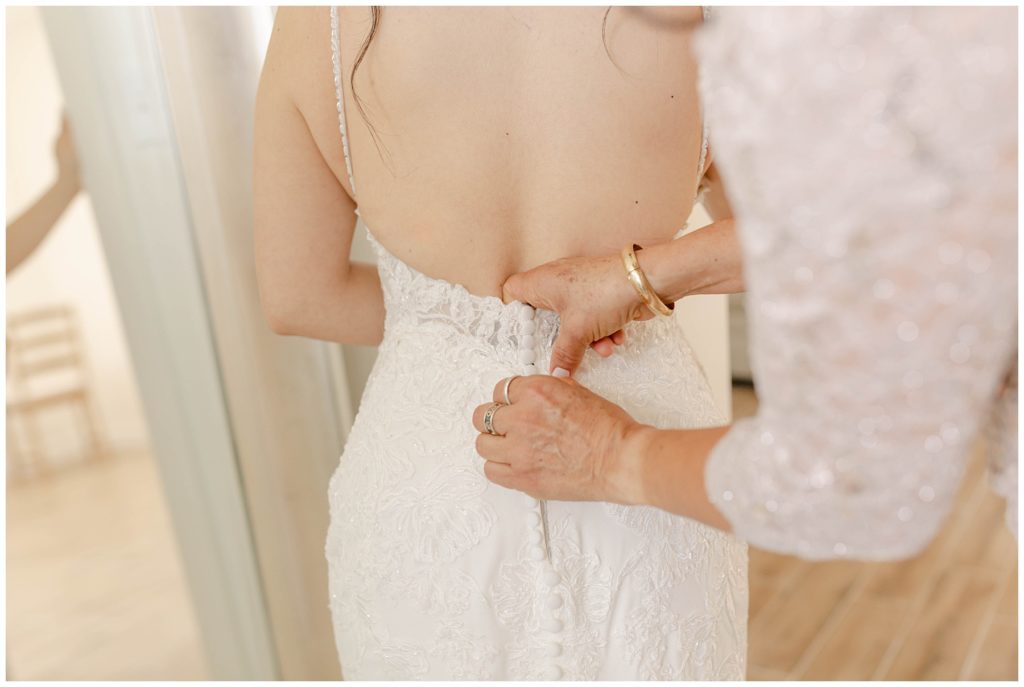 bride being buttoned into wedding gown