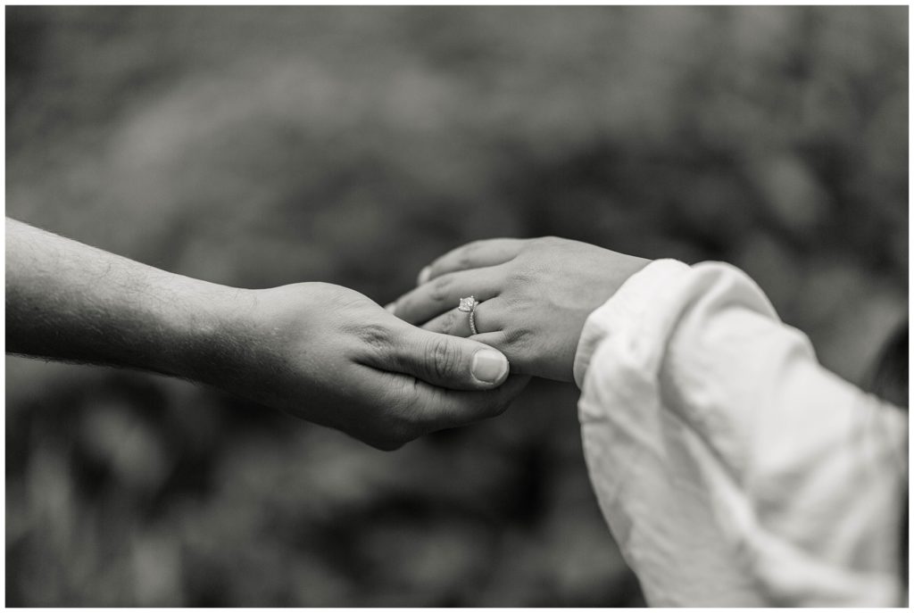 BW guy holding girl's hand showing engagement ring