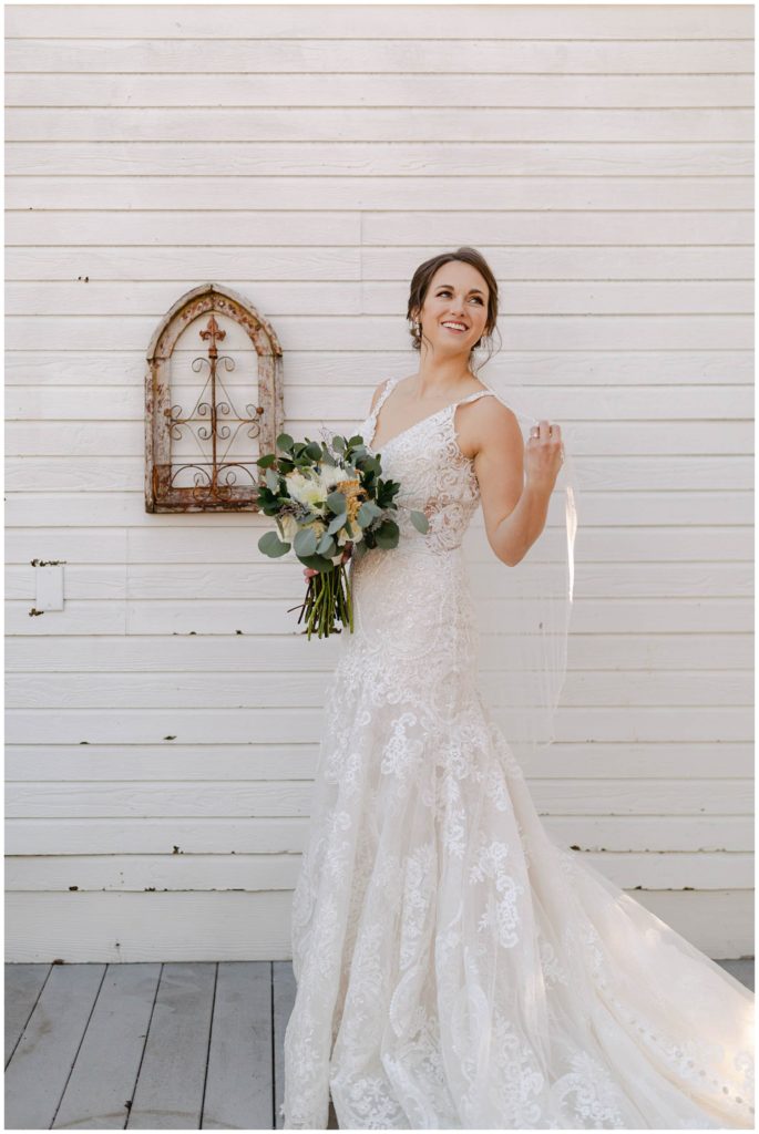 Bride sweeping veil over her shoulder and smiling