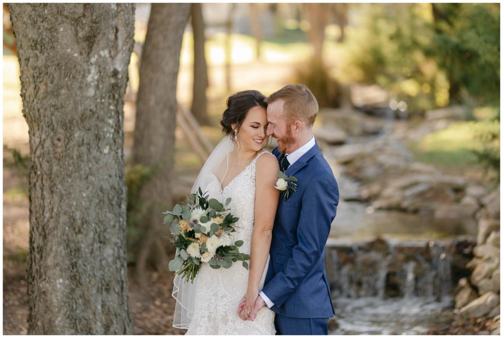 bride and groom embracing next to bubbling brook