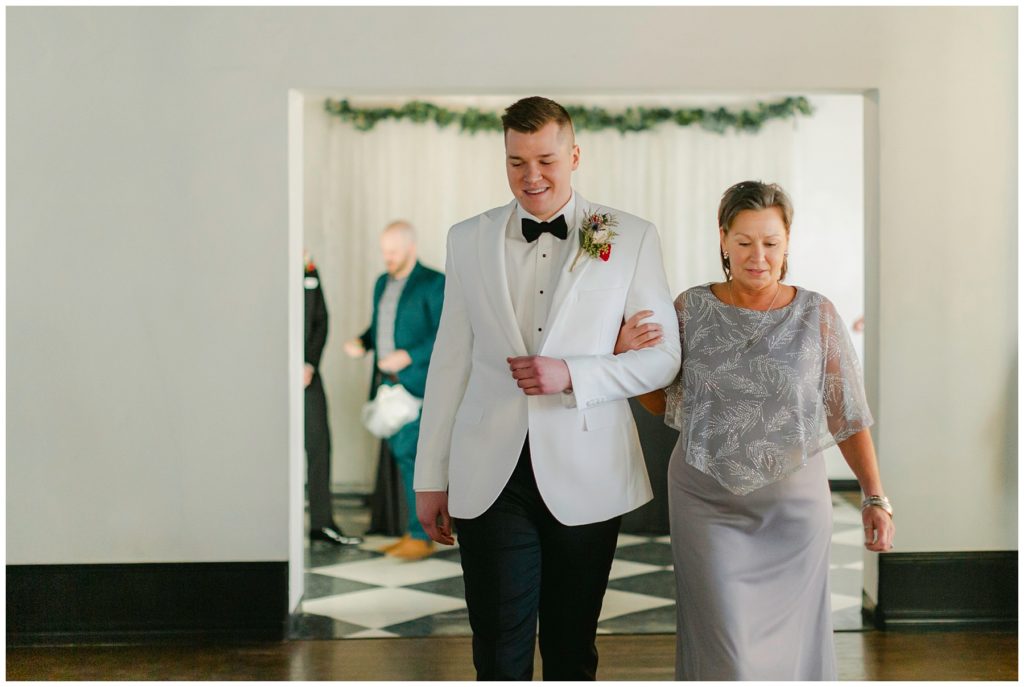 groom walking down aisle with mother