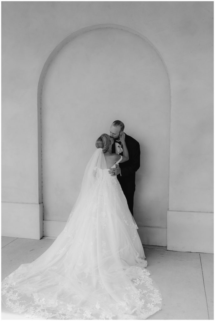 bw bride and groom kissing against wall