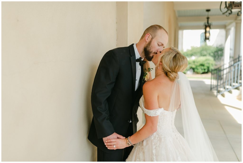 bw bride and groom kissing against wall South Carolina Catholic wedding