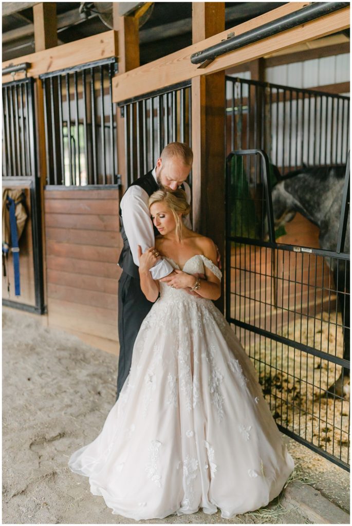 bride and groom hugging in horse stable