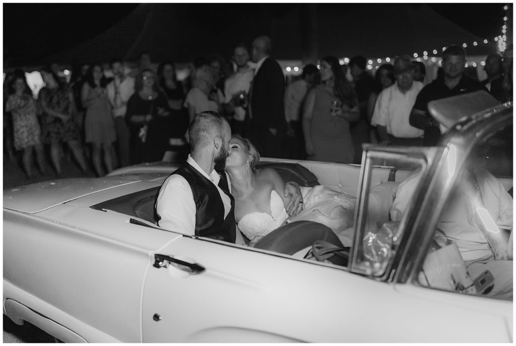 bride and groom kiss in wedding getaway car