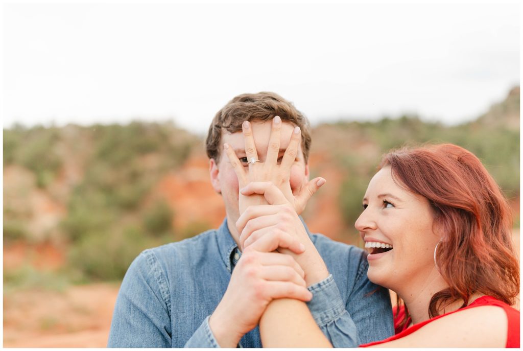 girl with engagement hand covering guys face