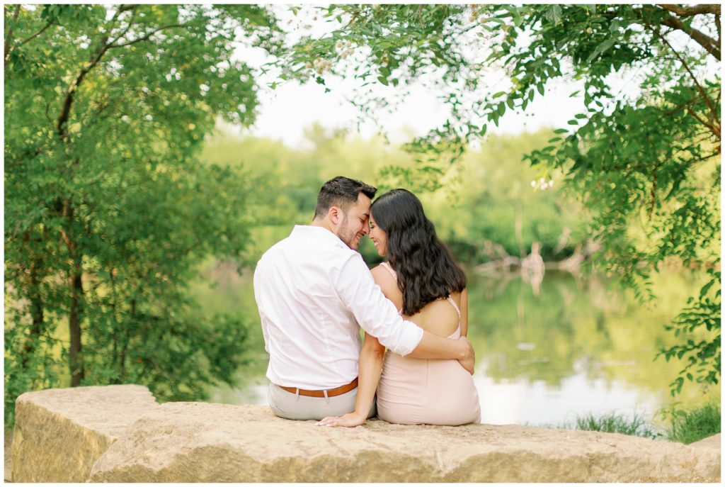 Couple sitting on rock nuzzling