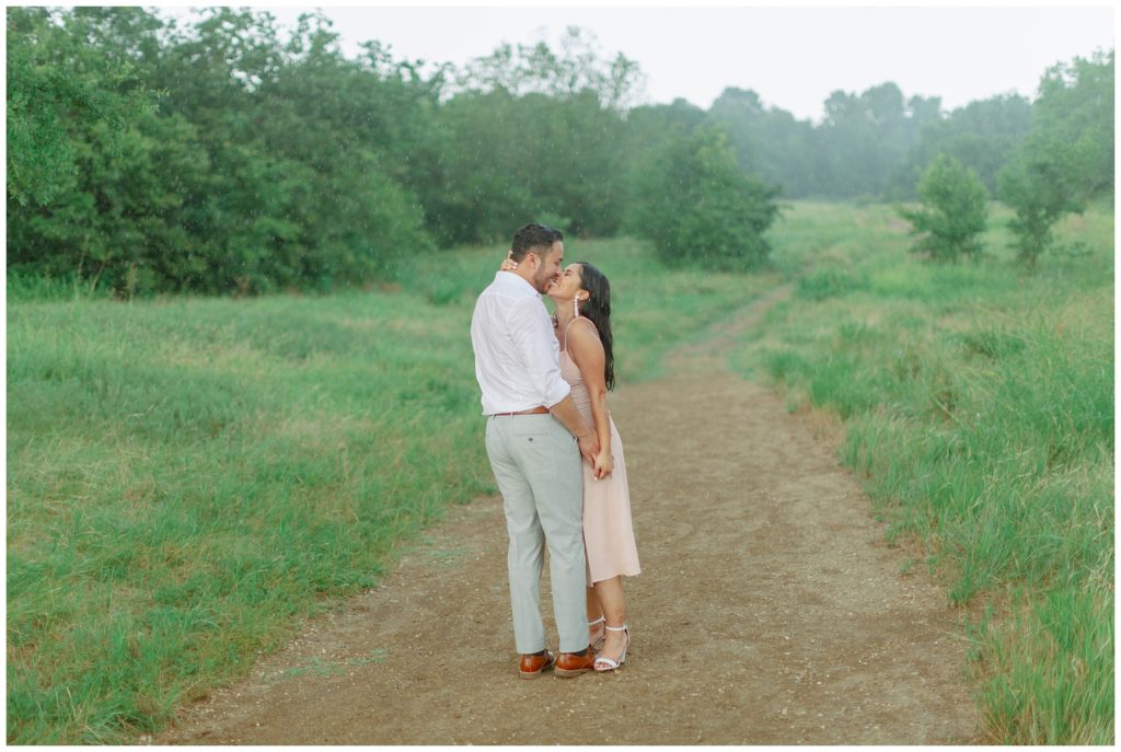 Couple kissing on dirt path in rain Couple kissing in the rain in Arbor Hills Nature Preserve Engagement