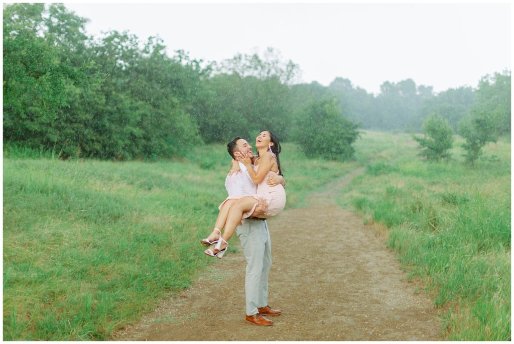 Guy twirling girl in rain laughing Couple kissing in the rain in Arbor Hills Nature Preserve Engagement