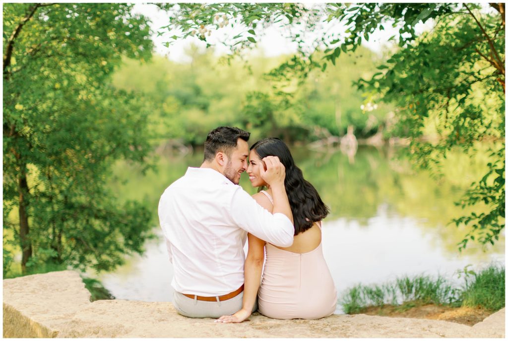 Couple sitting on rock nuzzling Couple kissing in the rain in Arbor Hills Nature Preserve Engagement