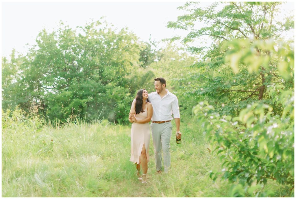 Couple walking through meadow in rain Couple kissing in the rain in Arbor Hills Nature Preserve Engagement