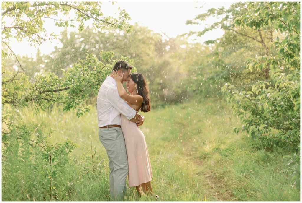 Couple embracing in meadow in rain Couple kissing in the rain in Arbor Hills Nature Preserve Engagement