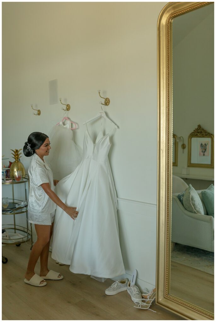 Bride standing next to wedding gown at The Orchard Texas wedding venue